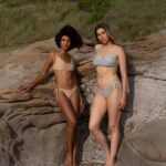 Two women in Salmastra bikinis on the rocks by the sea