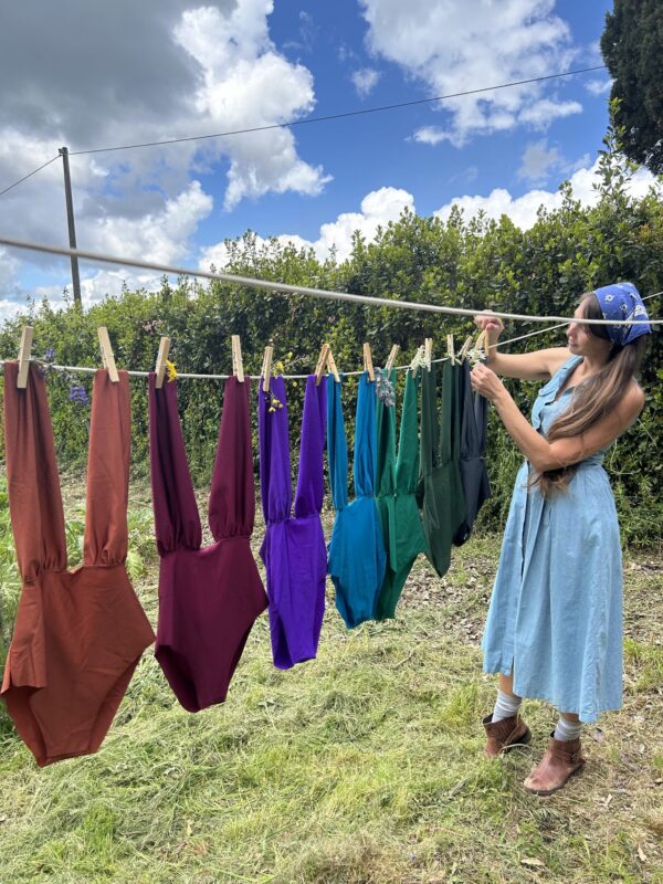 Colorful swimsuits hung out to dry on a line in the garden, under a blue sky