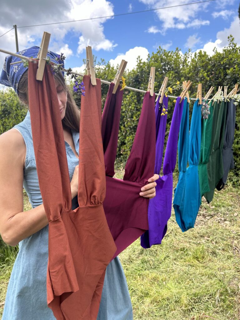 Costumi interi color ruggine, viola e verde stesi con le mollette