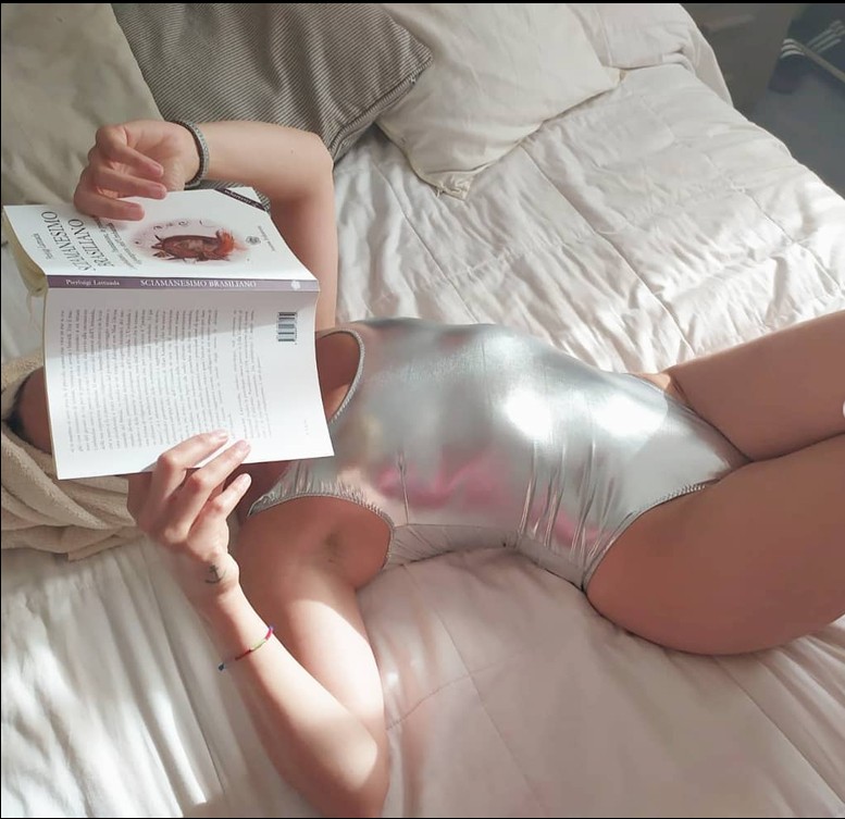 Ragazza che legge sul letto, in costume intero argento