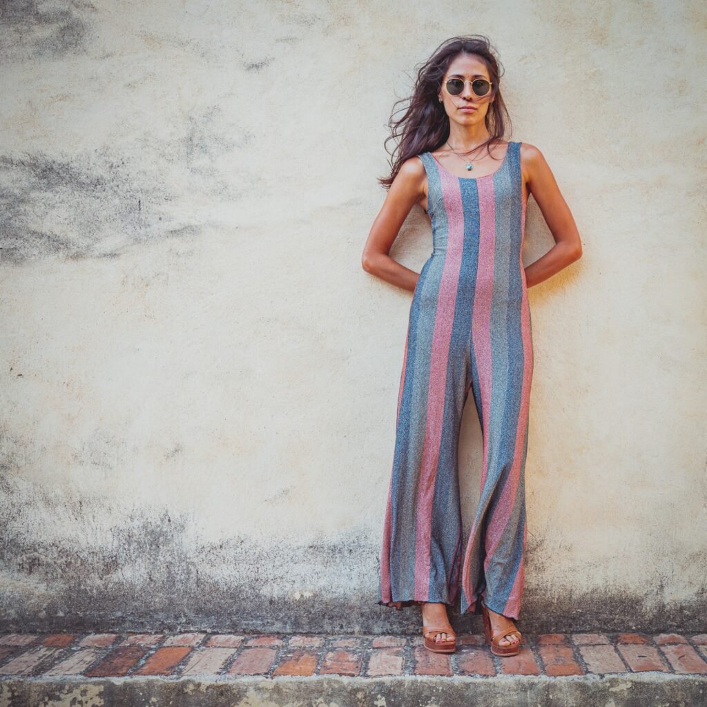 Ragazza in tuta a righe colorate brillanti davanti a un muro