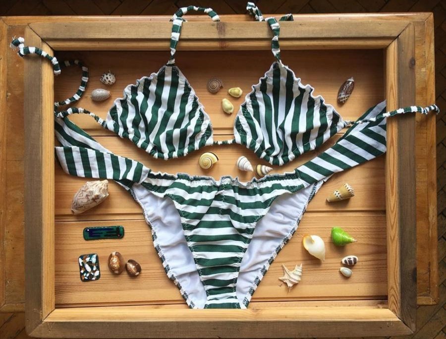 Bikini a righe verdi e bianche in una cassetta di legno con le conchiglie
