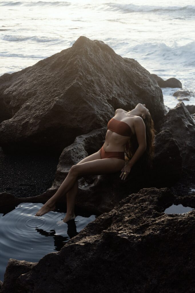 Girl in a bikini on the rocks at sunset