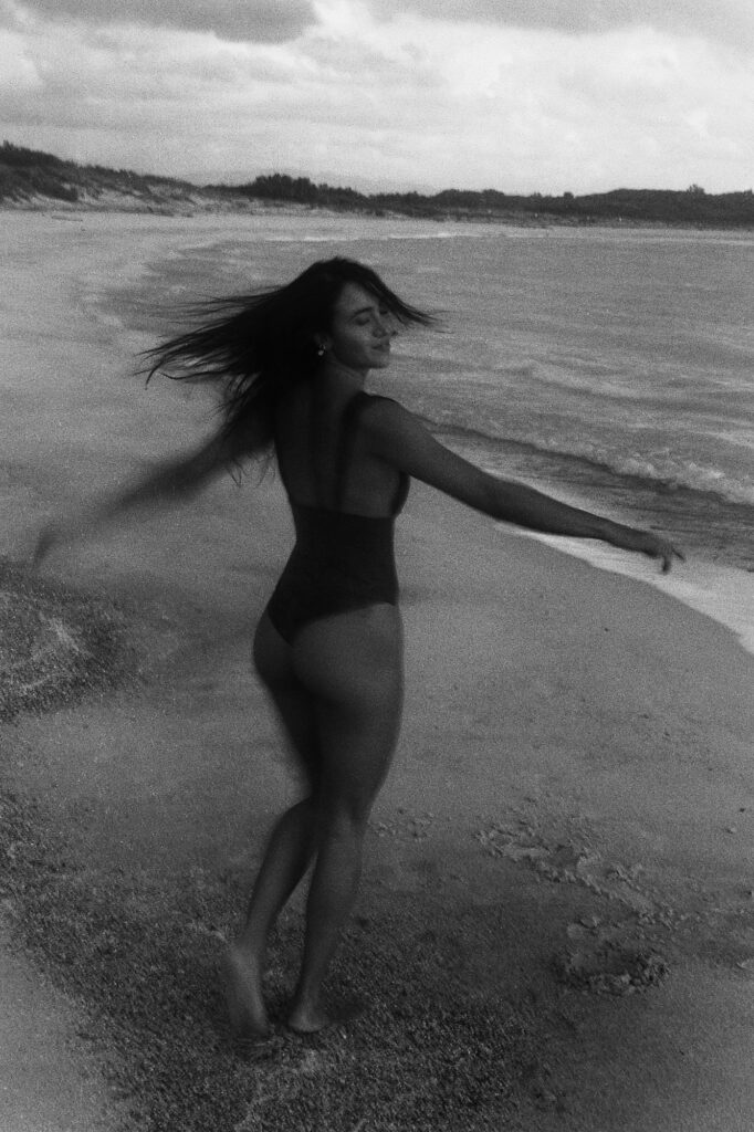 Girl in a one-piece dancing on the beach, black and white