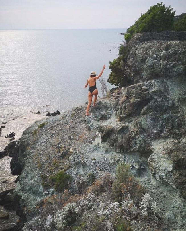 Girl in a swimsuit on the rocks above the sea