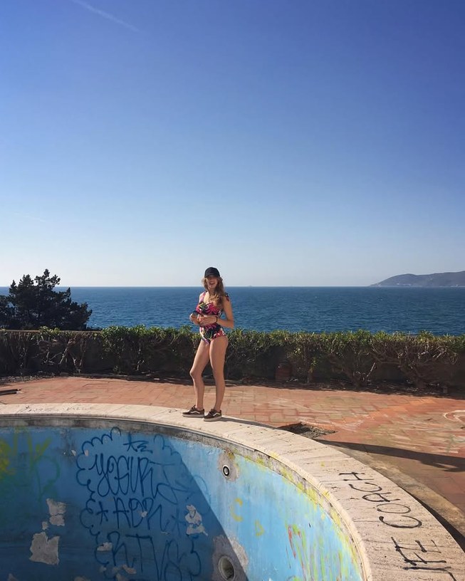 Girl in a bikini next to an empty pool by the sea