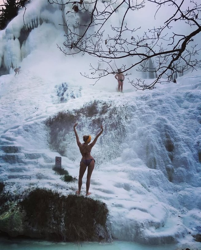 Girl in a bikini by snowy waterfalls