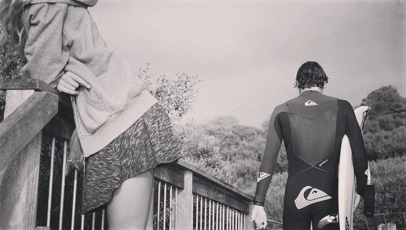 Surfer in a wetsuit with a board, black and white