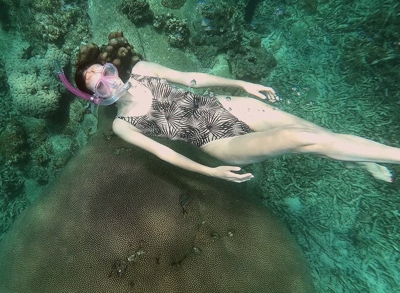 Girl with a mask swimming over coral