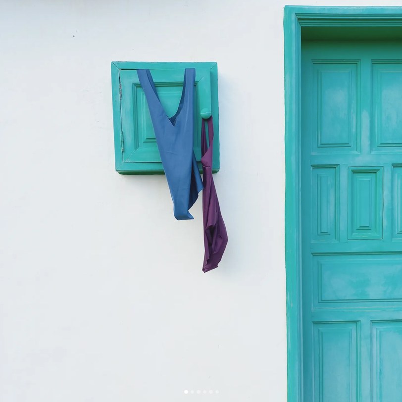 Blue swimsuit hanging from a small turquoise window