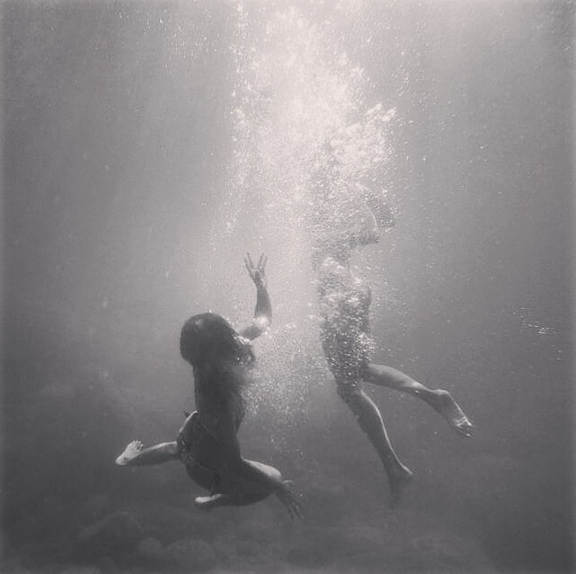 Two girls swimming underwater, black and white