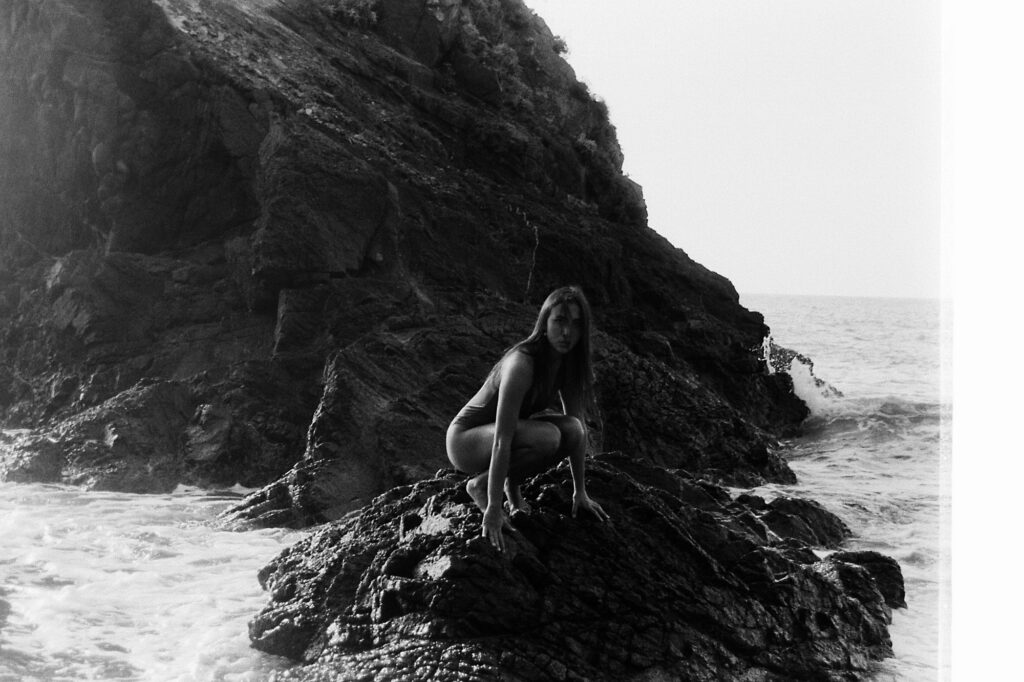 Girl crouching on the rocks, black and white