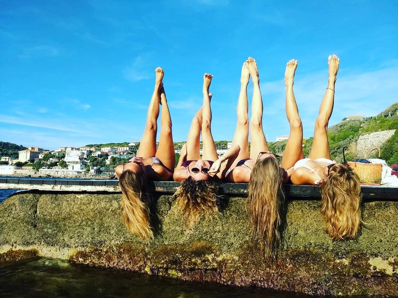 Girls lying on the pier with their legs up to the sky