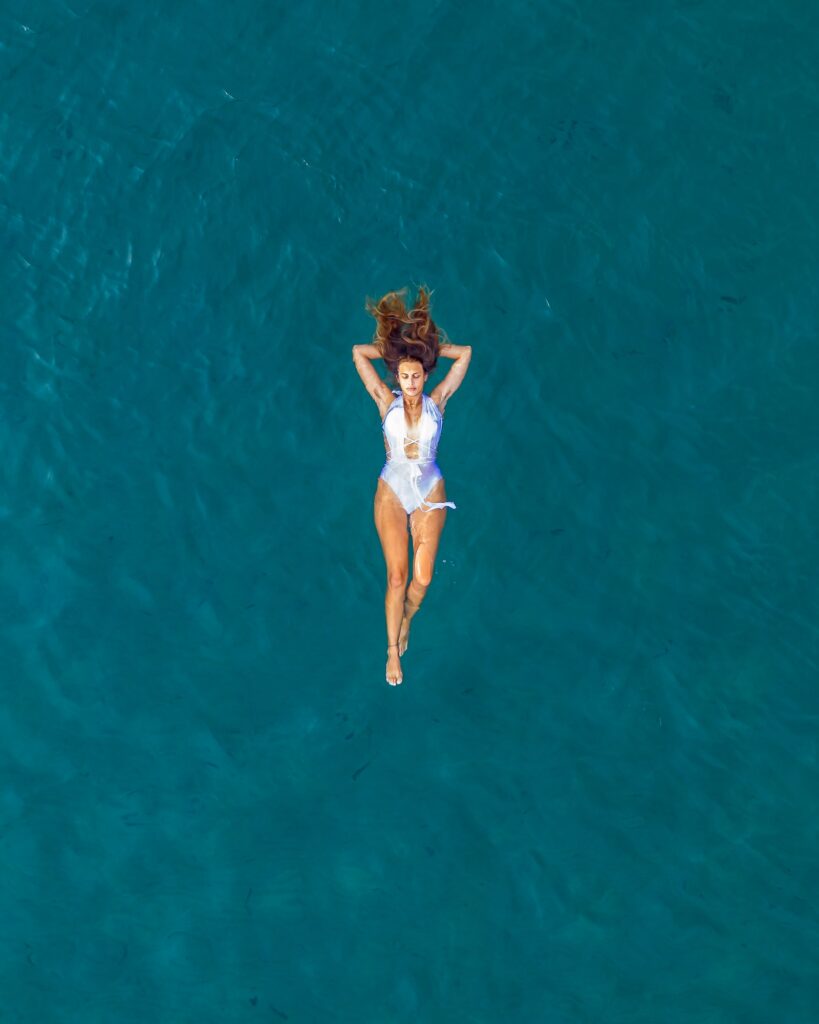 Girl in a white swimsuit floating in the open sea